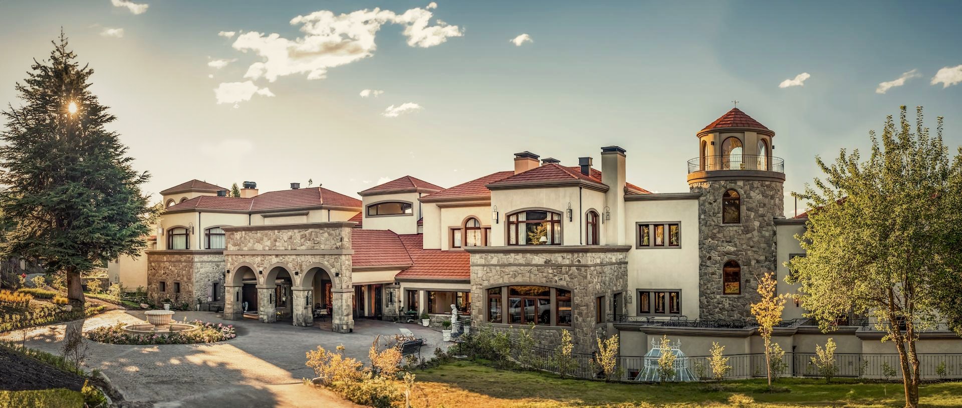 Main entrance of Villa Beluno luxury boutique hotel in Bariloche, Patagonia, Argentina, featuring Patagonian stone architecture and gardens at sunset