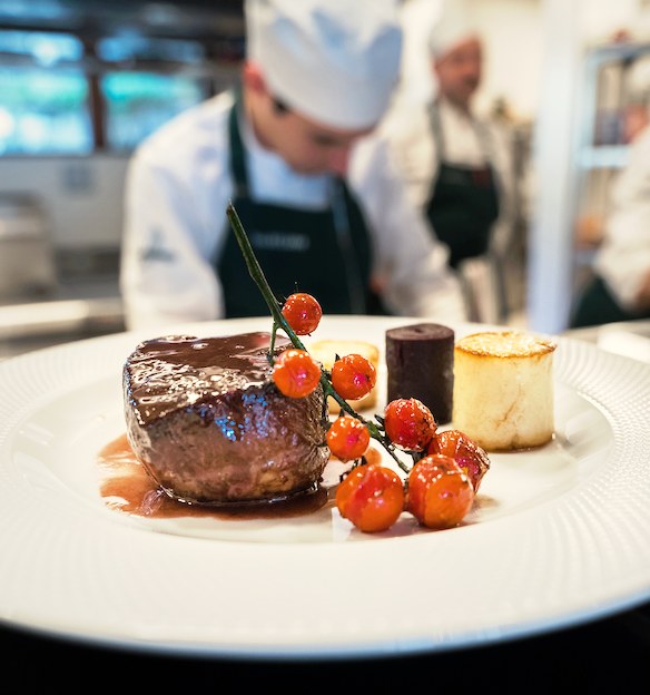 Beef tenderloin medallion with roasted cherry tomatoes and gratinated potato timbale plated in the kitchen of Avellana restaurant at Villa Beluno, Bariloche, Argentina