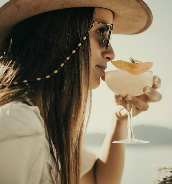 Woman drinking a signature cocktail by Nahuel Huapi Lake at Villa Beluno boutique retreat, Bariloche, Río Negro, Argentina